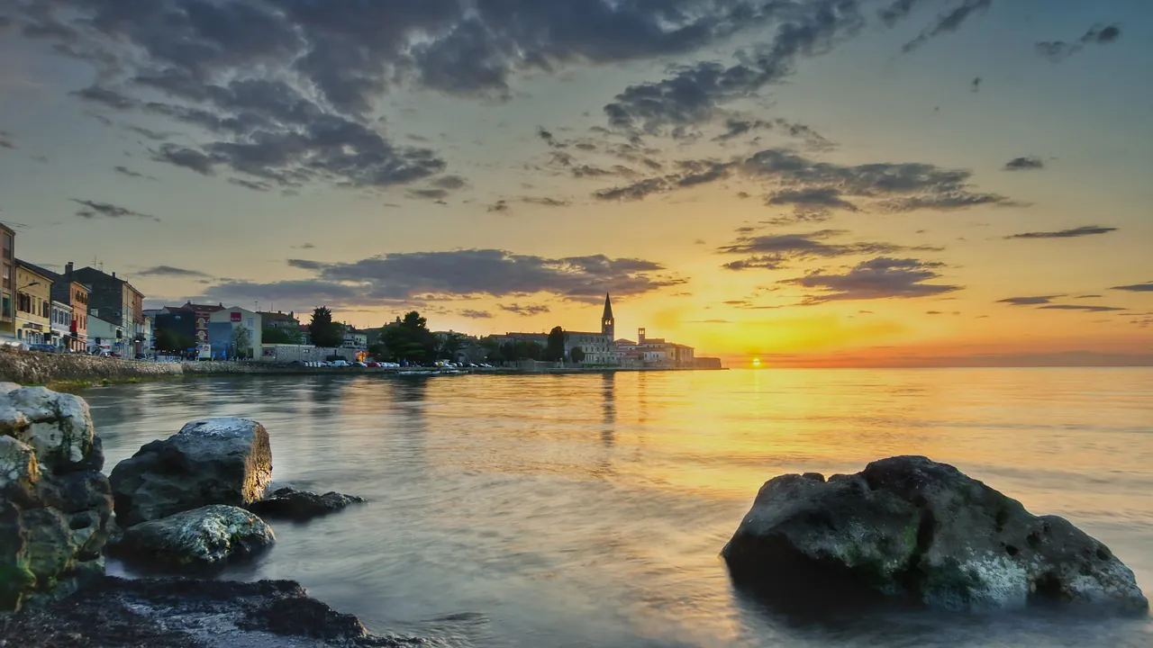 Peaceful Croatian coastline at sunset with natural rocks and calm sea in Porec