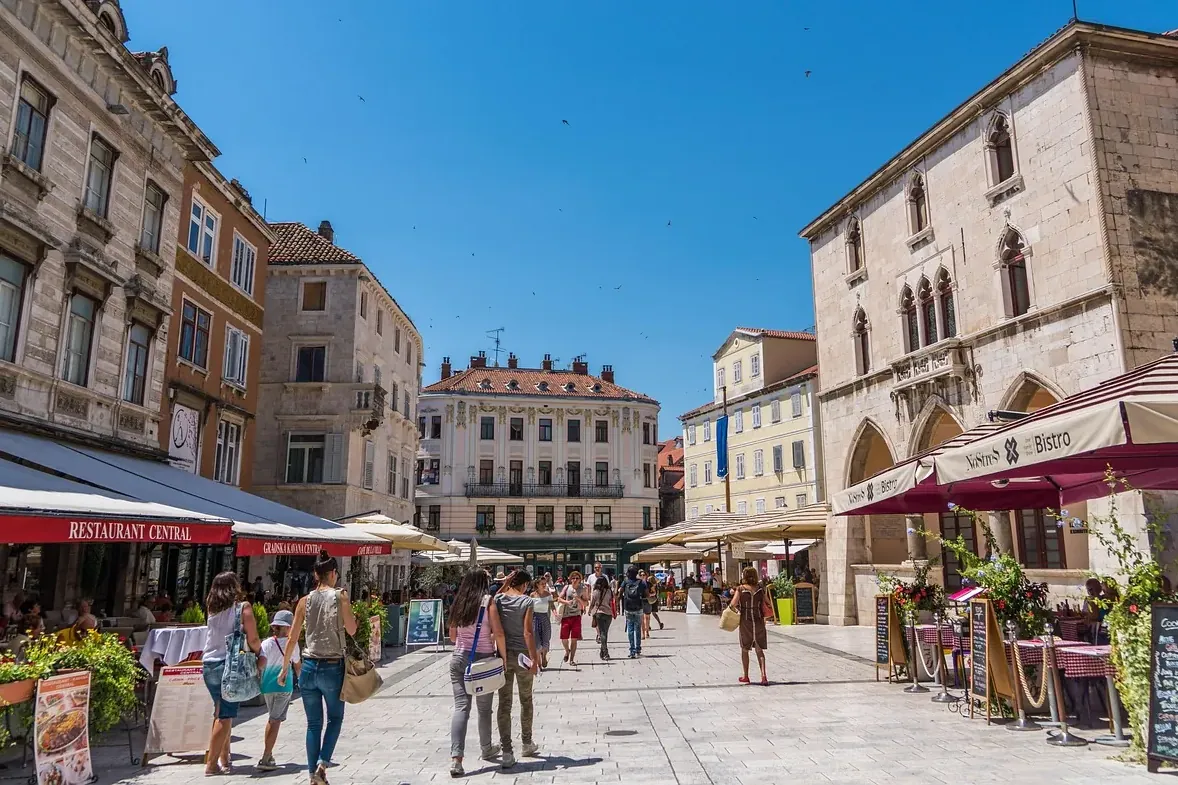 croatia-old-town-daily-life-locals-tourists-pjaca-square-split-cafes People walking through a historic Croatian old town Split during a calm summer day