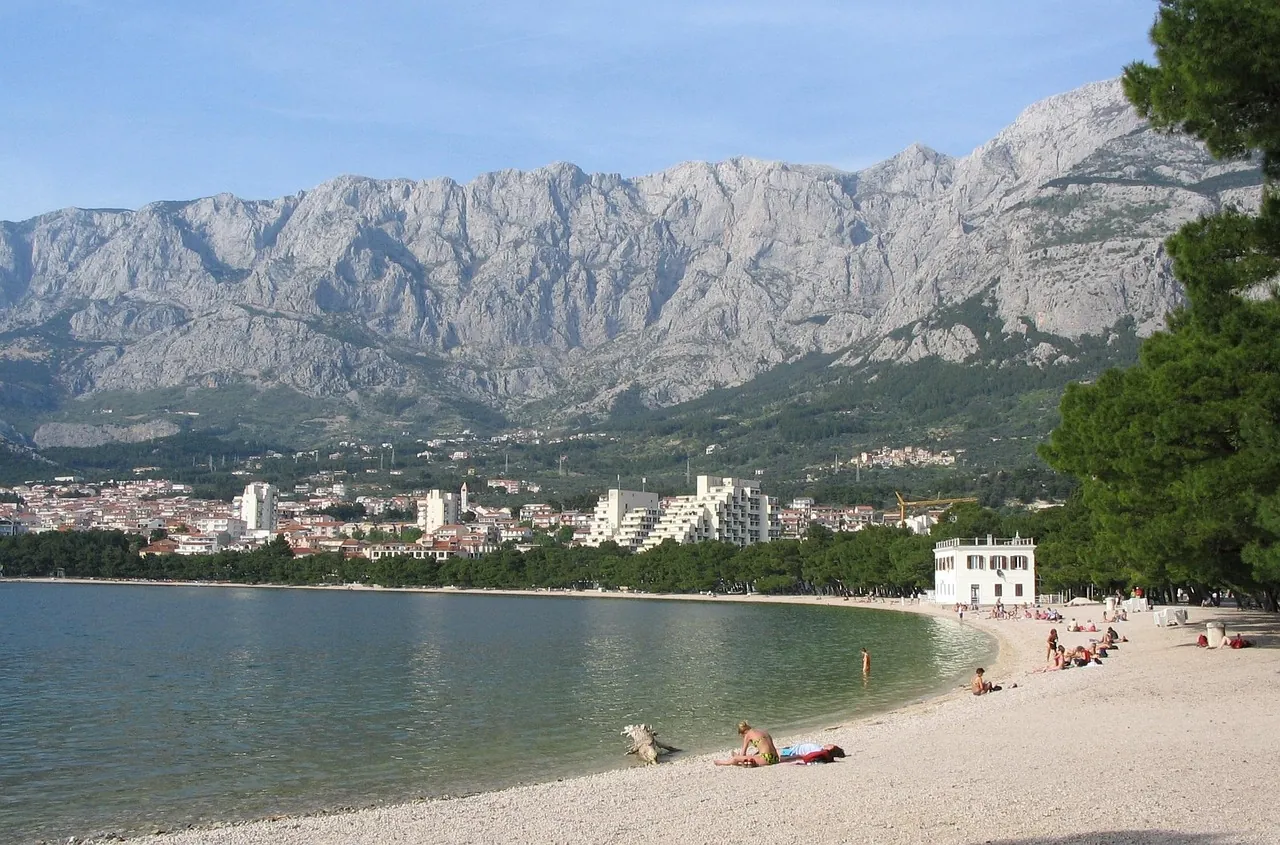 Pebble beach in Makarska on the Croatian coast with calm sea and mountain Biokovo in the background