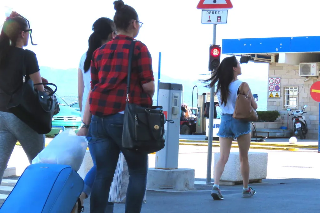 Travelers walking with luggage at a Croatian ferry port illustrating the reality of transport, travel timing and common mistakes tourists make in Croatia