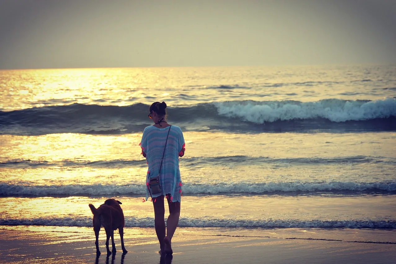 croatia-pet-friendly-beach-walk Woman walking a dog on a beach at sunset showing Croatia as a pet friendly destination