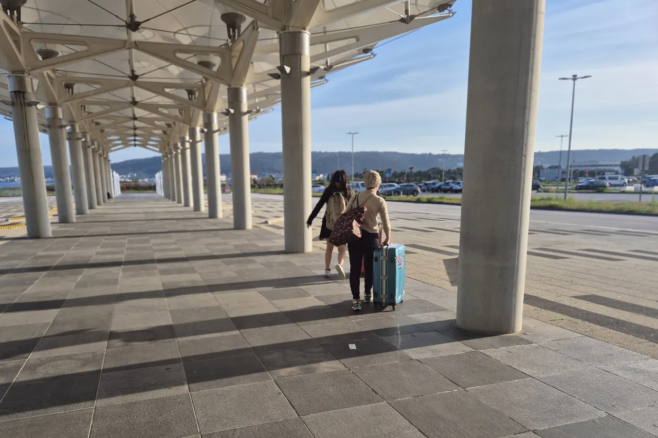 Passengers walking with luggage outside Split Airport terminal after arrival