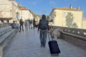 Travelling Croatia without a car in Dubrovnik Old Town, tourist walking with suitcase through historic street