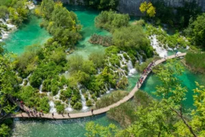 Visitors walking along wooden boardwalk above waterfalls at Plitvice Lakes, Croatia