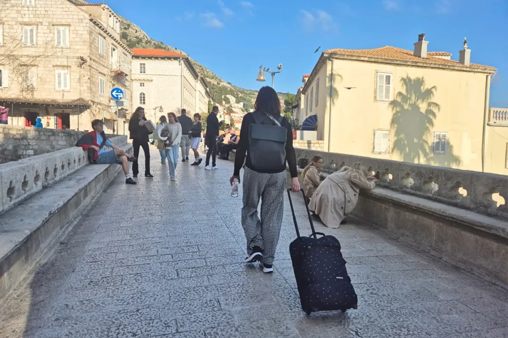Visitor walking with luggage towards Dubrovnik Old Town at Ploče Gate entrance as Dubrovnik reaches 2 million overnight stays