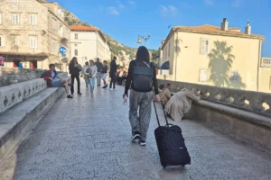 Visitor walking with luggage towards Dubrovnik Old Town at Ploče Gate entrance as Dubrovnik reaches 2 million overnight stays