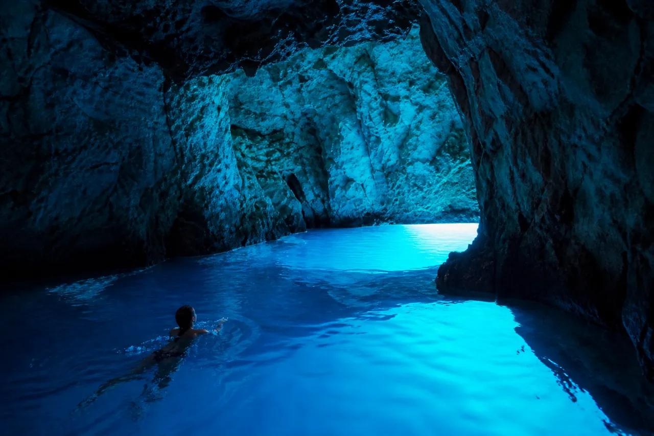 blue-cave-tour-swimmer-croatia-day-trip A swimmer in the glowing blue water inside a Blue cave in Biševo, Croatia