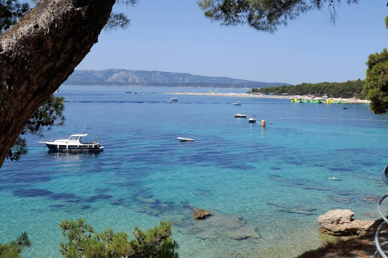 brac-bol-zlatni-rat-view-coast. View of Zlatni Rat beach near Bol on Brač island, with clear turquoise water and boats anchored along the coast.